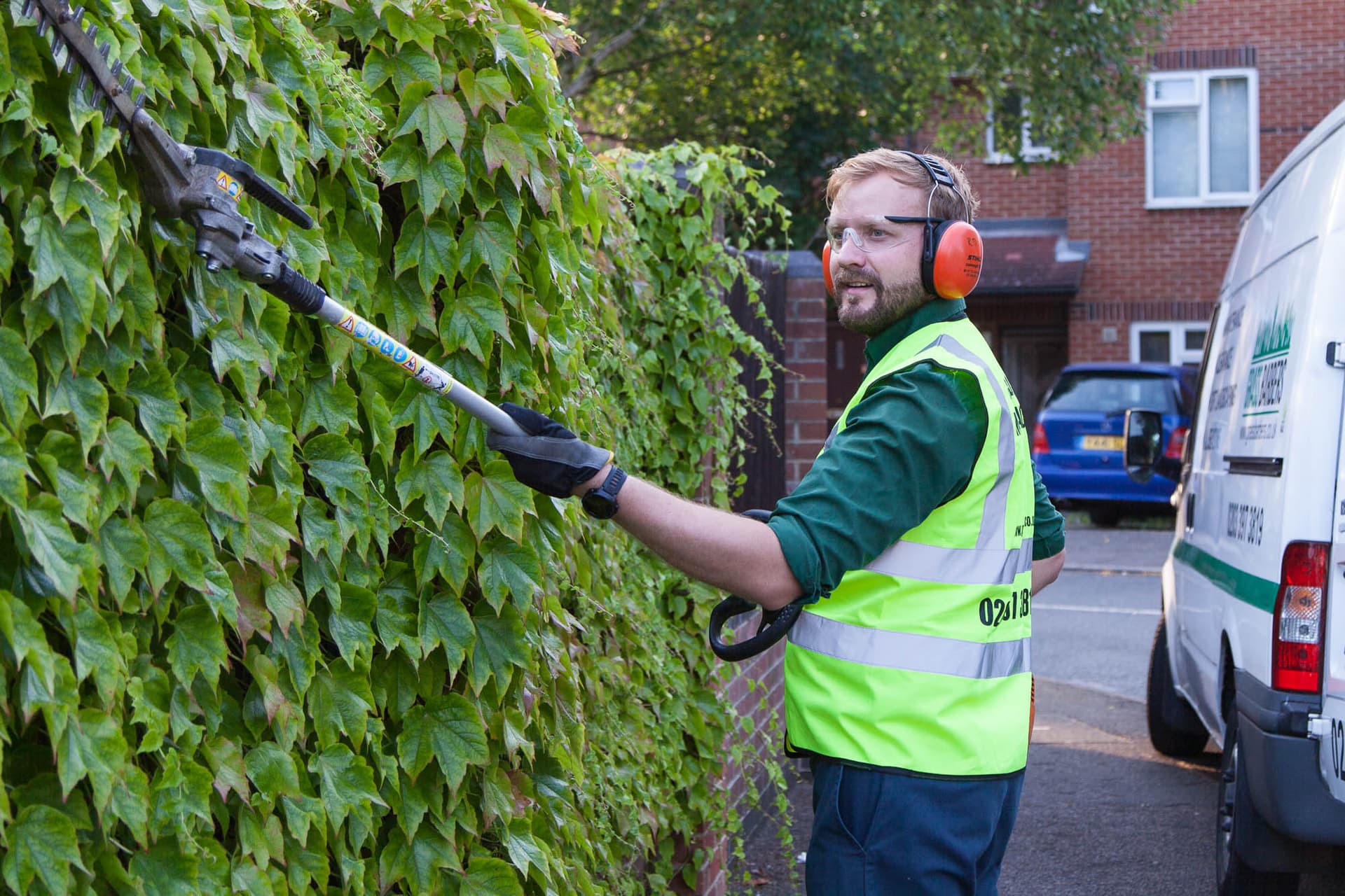 Grass Barbers professional field team performing expert hedge trimming with specialised power tools